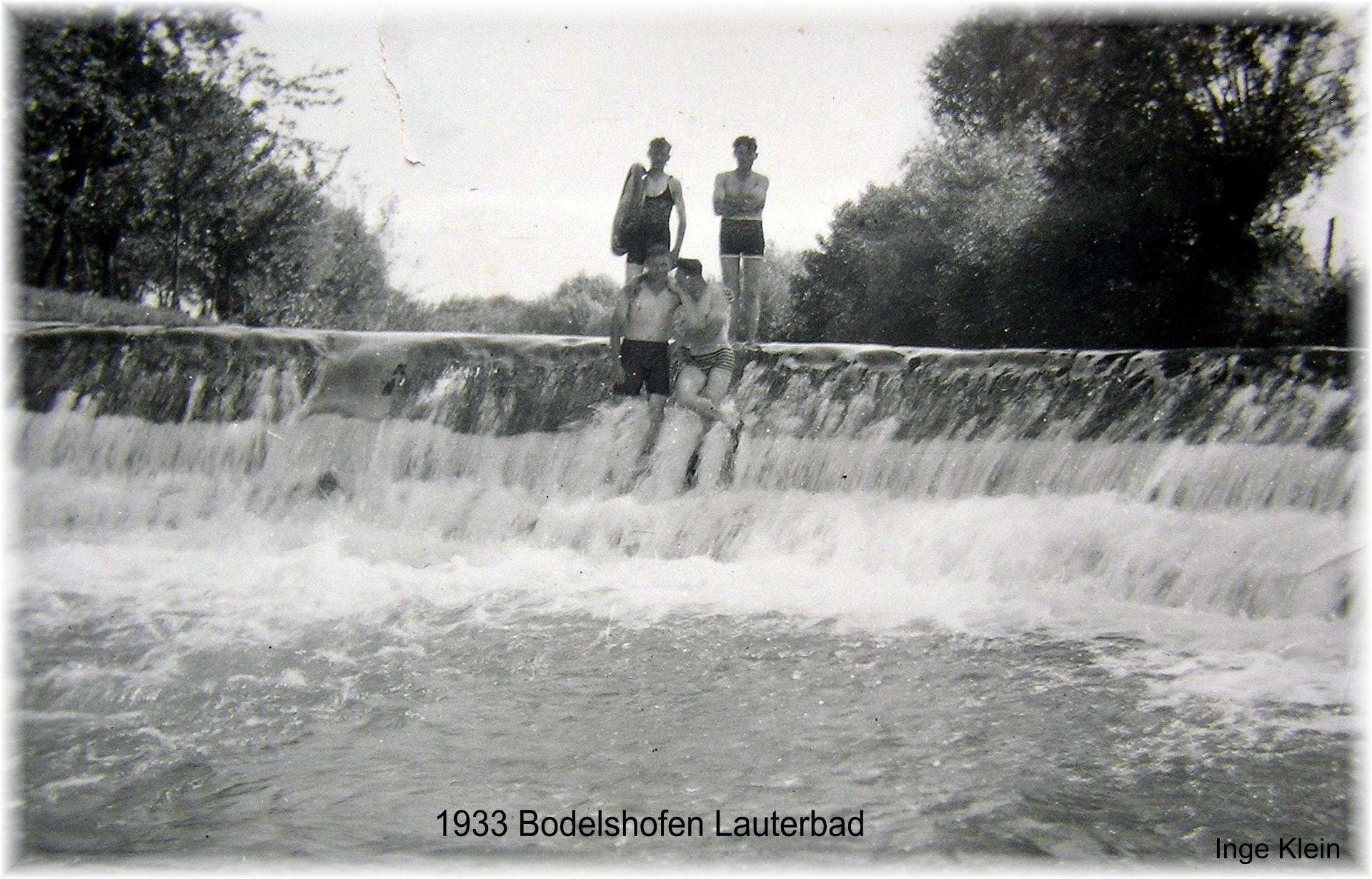 Schwarzweißaufnahme vier junger Männer in Badekleidung an einer Wasserstufe der Lauter