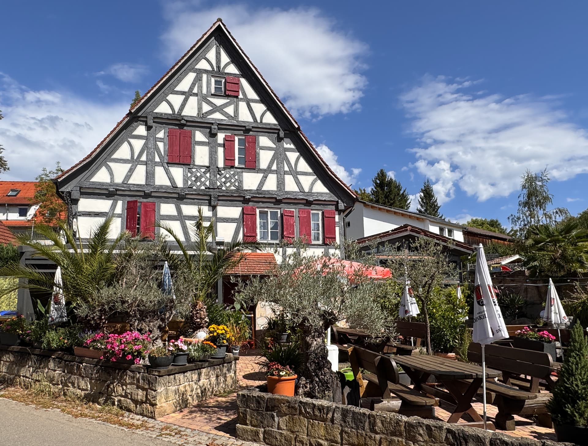 Fachwerkhaus des Eichenkellers mit Biergarten, Holztischen und Sonnenschirmen