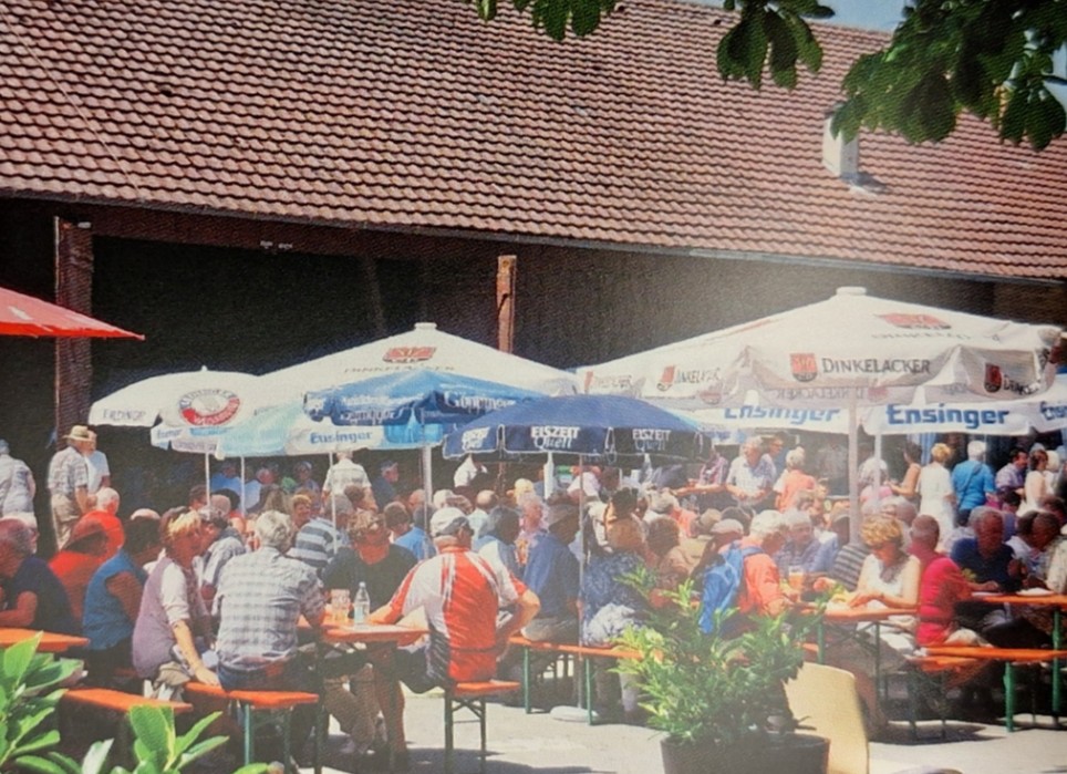 Festbetrieb mit Sonnenschirmen und Biertischen vor der großen Scheune auf dem Hof